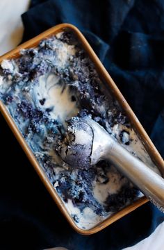 an ice cream dish with blueberries in it and a metal spoon sitting next to it