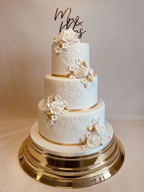 Amberley, popular 3 tier design decorated with edible lace detail and clusters of sugar flowers in white and gold, perfect for a festive Chrismas season wedding White Wedding Cakes, Gold And White Wedding Cake, White And Gold Wedding Cake, White And Gold Wedding Cake Elegant, Gold Wedding Cake, Wedding Cake Roses, Wedding Cake With Gold, Wedding Cakes Gold, Wedding Cakes Gold And White