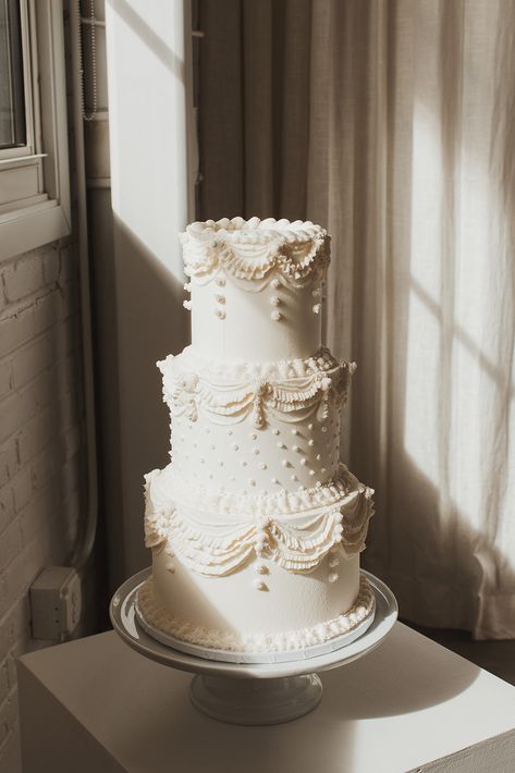 A white three tiered wedding cake with vintage swap piping and polka dots Wedding Cake White Piping, Wedding Cakes Retro, Vintage Cake Aesthetic Wedding, Vintage Wedding Cake With Topper, 1950 Wedding Cake, Vintage Wedding Cake One Tier, Wedding Cake With Piping Detail, Old Style Wedding Cakes, All White Vintage Cake