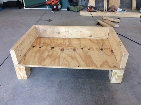 DIY dog bed. Made from 4x4 post wood, plywood, and 2x6s. Going to sand the corners and paint it all gray, then make a cushion and pray my a-hole dog doesn't chew it up! Wooden Dog Bed Frame, Wood Dog Bed, Wooden Dog Bed, Corner Dog Bed, Wood Frame Dog Bed, Pallet Dog Beds, Dog Bed Diy Large, Farmhouse Dog Beds, Diy Raised Dog Bed