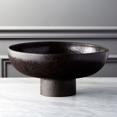 Rise up. Unique stoneware bowl stands tall as a stately centerpiece or bookshelf display. Finished with two reactive glazes shiny and matte bowl has an authentic aged appeal. Pedestal gives it just enough lift to stand out. Black Pedestal Bowl is a CB2 exclusive. -Stoneware with reactive glaze -Each piece will be unique -For decorative use only -Wipe clean -Made in Portugal