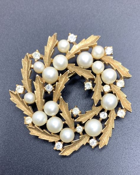 This delicate Trifari brooch is in a shape of a golden leaf wreath with faux pearls of different sizes and clear rhinestones. The diameter of the jewel is 4.5 cm (1.8''). Signed on the back Trifari with a crowned T and a copyright symbol. The brooch was featured on one of the Trifari advertisements in 1958 (please check the reference in the photo carousel). Brooch, Jewellery, Vintage, Trifari Brooch, Vintage Jewelry, Crown Trifari, Pearl Brooch, Jewel, Jewelry