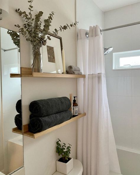 This small bathroom is dressed up with a flowy chiffon shower curtain in a bright shade of white to match the white square tiles along the shower walls. A set of natural wood floating shelves can be styled with a calming arrangement of eucalyptus, black bath towels, and candles. Bath, Home Décor, White Shower Curtain Bathroom, Elegant Shower Curtains, Bathroom Shower Curtains, Shower Curtain Decor, Bathroom Curtains, Shower Walls, Guest Bathroom Towels