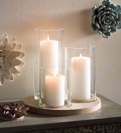 Three glass vases of varying heights beautifully blend with a modern beechwood tray, resulting in a display that is radiant and inviting with the addition of candles or blooms. Easily update any space with an elegant modern vibe by placing this trio atop a side-table, in your outdoor area, or as a centerpiece. We especially love it mixed with twinkle lights and a simple floral arrangement. V4918,Hurricane/Vase Platter Set,beechwood tray,wood tray,planter,candle Dining Table Candle Centerpiece, Glass Vases Decor Ideas, Glass Candle Centerpieces, Glass Tray Decor, Glass Candle Holders, Candle Arrangements Living Room, Glass Vase Decor, Candle Table, Coffee Table Centerpiece Ideas