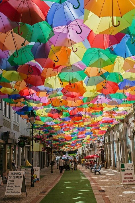 Águeda's Umbrella Sky Project began in 2011 as a part of the Portuguese city's annual Ágitagueda Art Festival. Each summer, when temperatures soar, a handful of Águeda's narrow streets feature canopies of colorful umbrellas that provide shade to the pedestrians below. Destinations, Trips, Trip, Europe, Beautiful Places In The World, Places To Visit, Beautiful Places, Places To Travel, Nature Travel