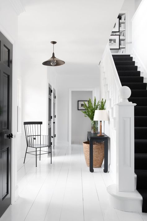 To create an urban, almost loftlike feeling, Mazzarini painted all of the floors high-gloss white. Touches of jet-black offer a bit of dramatic flair. The high-shine doors are painted Hollandlac by Fine Paints of Europe, and the stairs are covered in black sisal by Mischa Carpet. The metal chair is from Terrain, while the lamp is a vintage find from Jon Howell Antiques. Architectural Digest, Interior, Interior Design, Coastal Interiors, Interieur, Long Island, Apartment Entrance, Flooring Trends, White Beach House