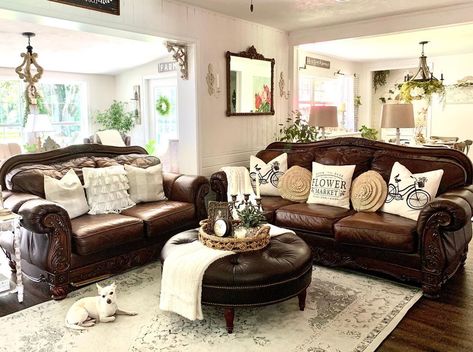This farmhouse living room boasts a brown leather couch with antique dark wood frame seated next to a matching loveseat. A round tufted brown leather ottoman is placed in front of the couch on a beige and gray vintage rug. Interior, Leather Couch Living Room Decor, Brown Leather Living Room Furniture, Brown Leather Sofa Living Room, Leather Sofa Living Room, Brown Leather Couch Living Room, Leather Couches Living Room, Leather Couch Decorating, Brown Leather Couch Decor
