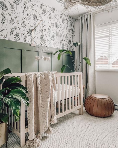 Neutral nursery rug hosts a light wood crib with a beige tasseled blanket draped over the side. Green board and batten is paired with foliage wallpaper to create an accent wall. Chestnut colored pouf and potted plants offer this room a natural look. Design, Bebe, Wallpaper, Dekorasyon, Baby Boy Rooms, Beige, Lookbook