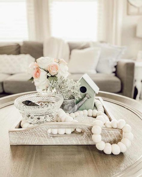 If you have a round natural-wood coffee table, you can emphasize its farmhouse style with accessories and accents. Notice how starting with a distressed white wooden tray adds the true essence of rustic decor. By adding an ornate crystal vase, you can achieve a pleasing vintage flavor, or substitute a floral-painted ceramic vase, if you like. Design, Home Décor, Decoration, Farmhouse Coffee Table Decor, Farmhouse Table Decor, Coffee Table Centerpiece Ideas, Rustic Coffee Tables, Table Tray Decor Ideas, Decorating Coffee Tables