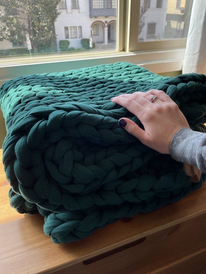 a woman's hand on top of a green blanket in front of a window