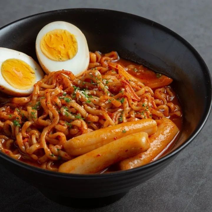 a black bowl filled with noodles and hard boiled eggs