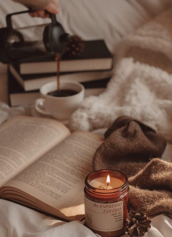 an open book and candle on a bed