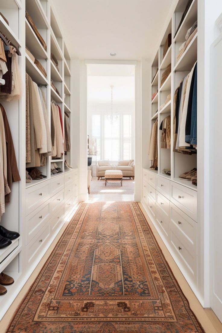 a walk in closet filled with lots of white shelves and drawers next to a rug