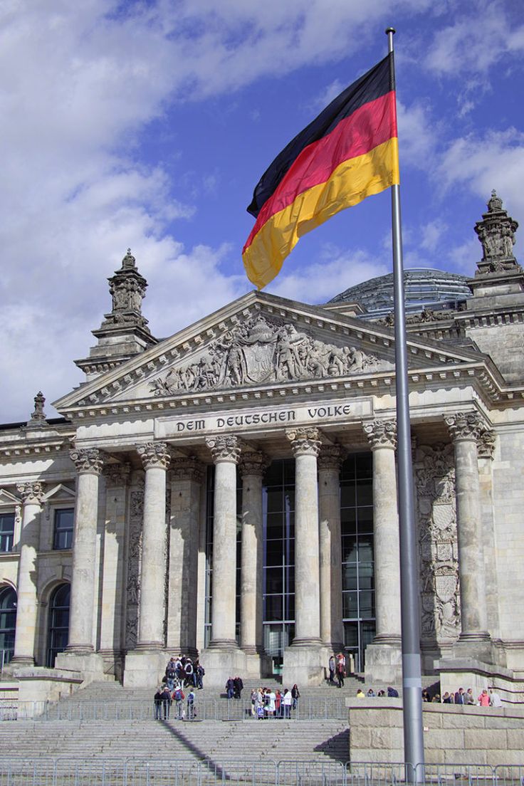 a german flag flying in front of a large building with columns and pillars on it