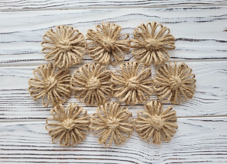 several pieces of jute are arranged on a white wooden surface with knots in the shape of flowers
