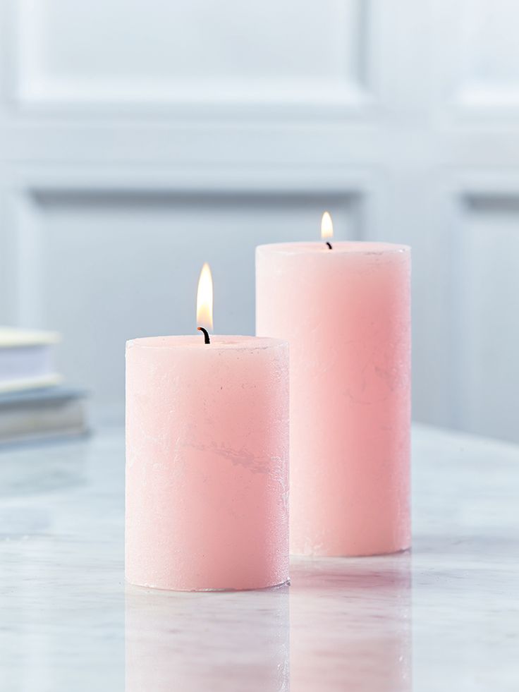 two pink candles sitting on top of a table