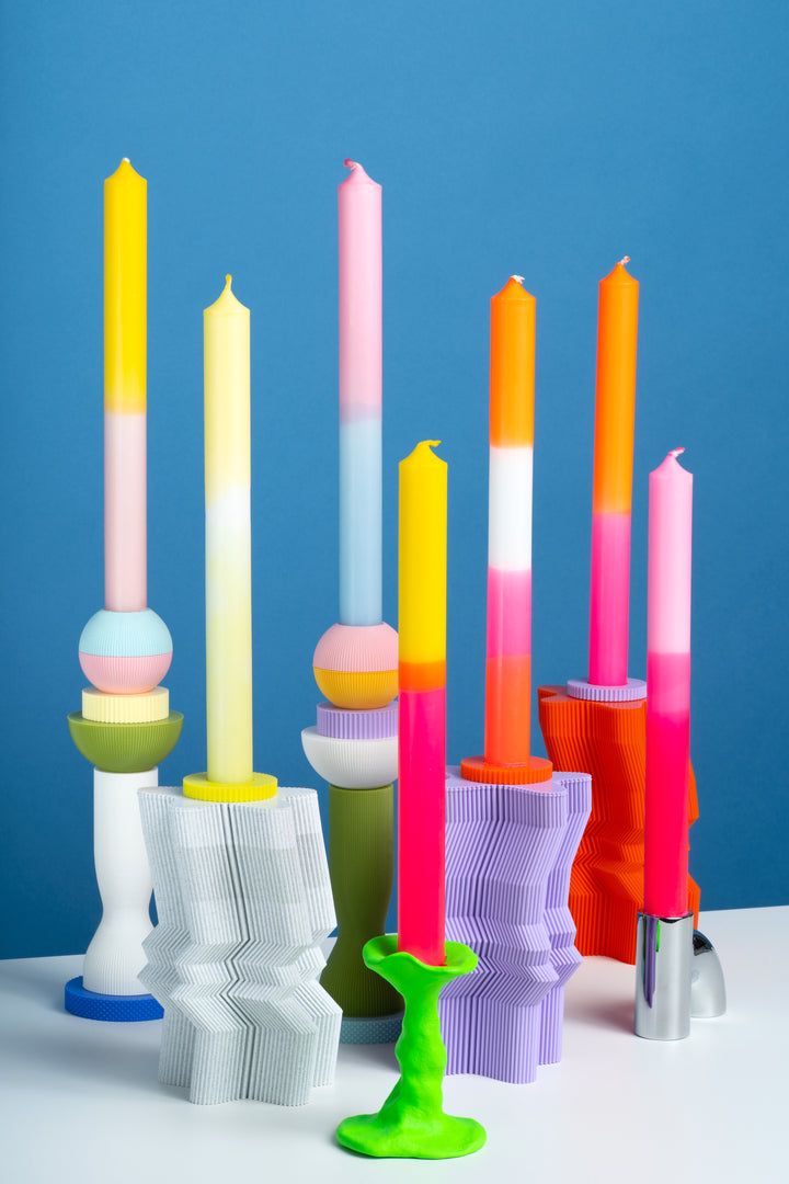 many different colored candles on a white table