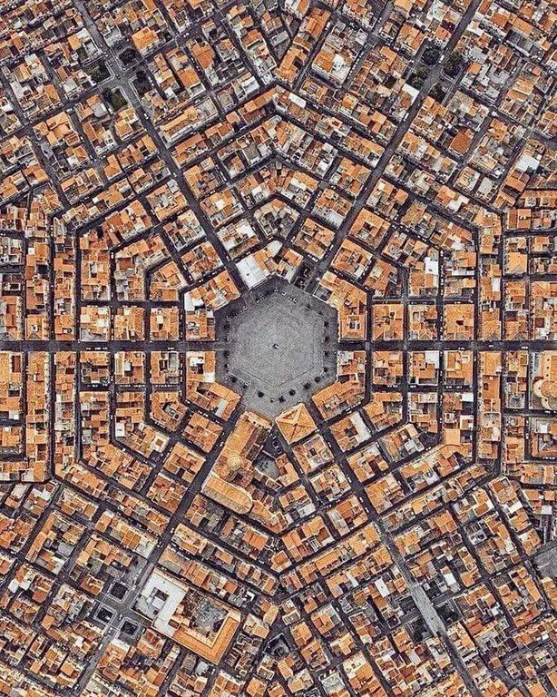 an aerial view of a city with lots of orange buildings on the sides and a black square in the middle