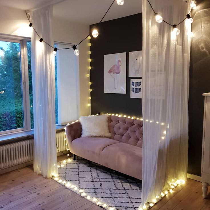 a living room filled with furniture and string lights on the wall next to a window