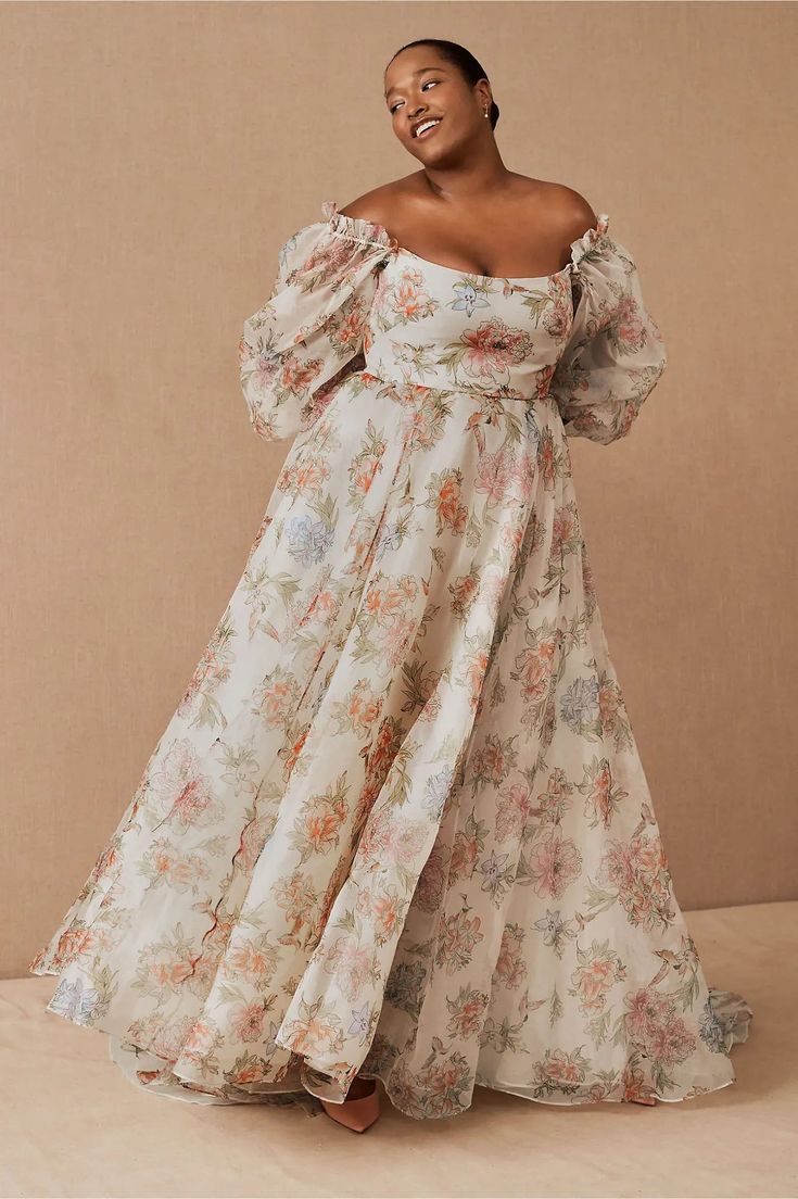 a woman in a floral dress poses for the camera
