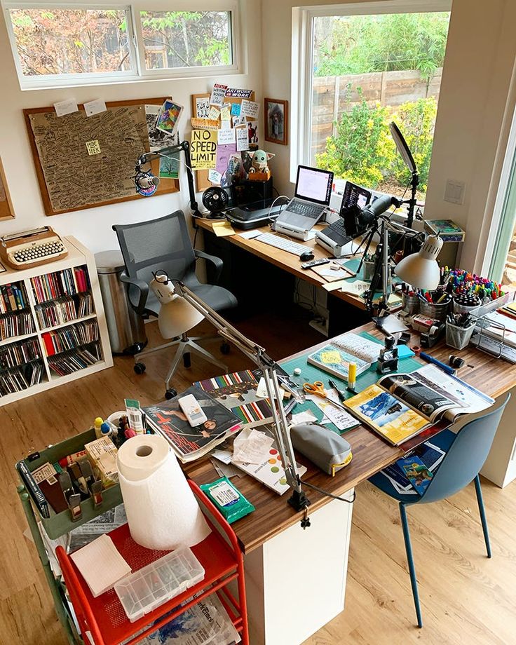 a home office with lots of clutter on the desk and shelves full of books