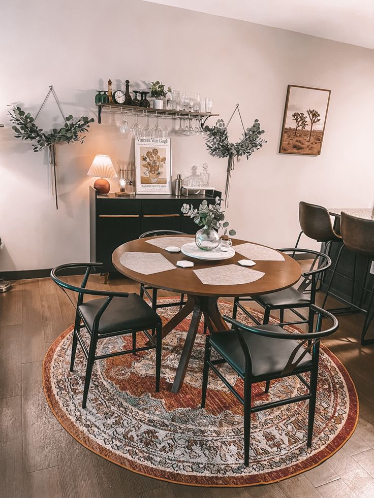 a dining room table with four chairs and a rug on the floor in front of it