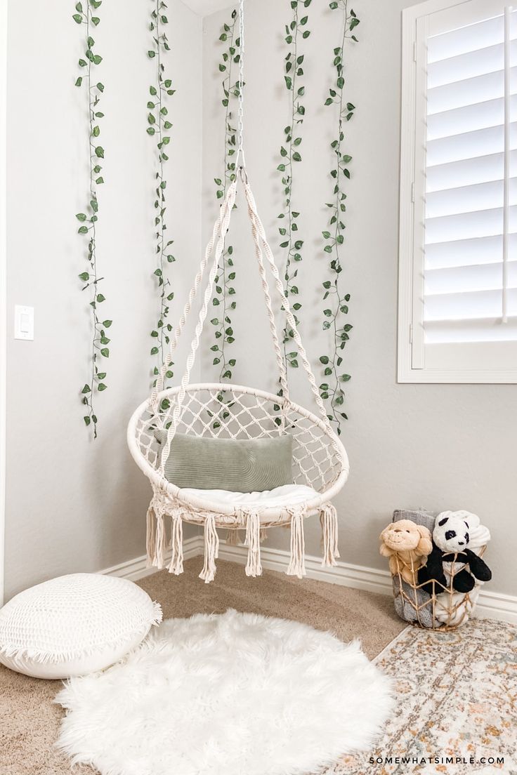 a white hammock hanging in the corner of a room with greenery on the wall