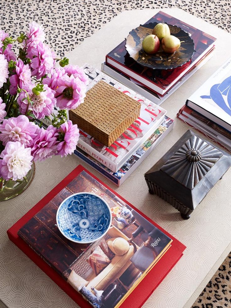 a table topped with lots of books and vases filled with flowers on top of it