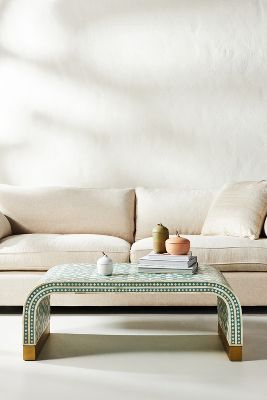 a white couch sitting next to a table on top of a hard wood floor in front of a white wall