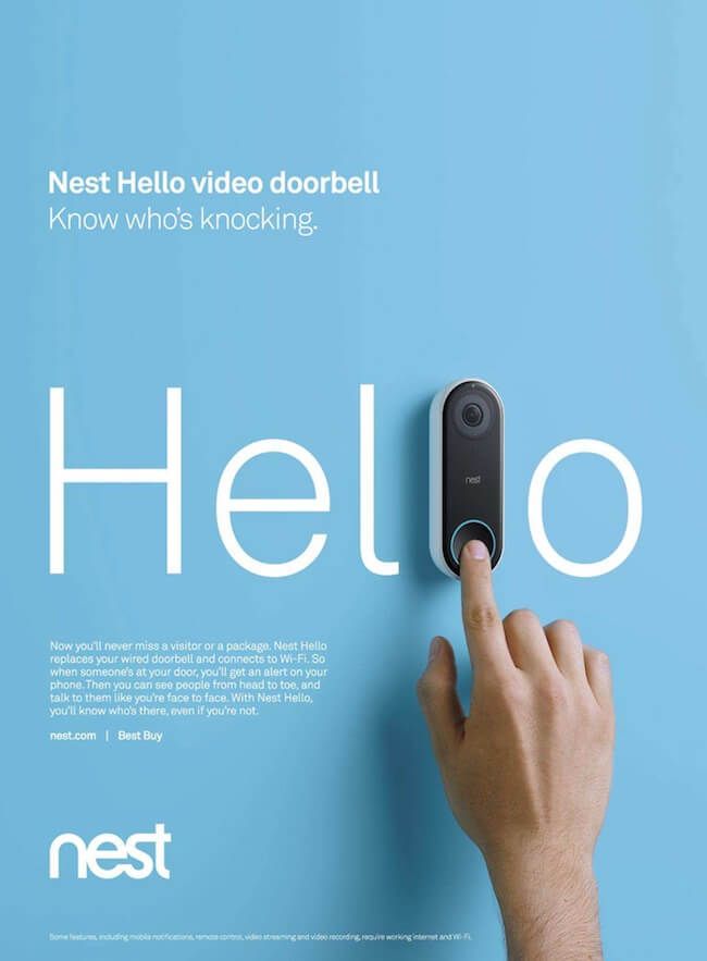 a hand pressing the word hello on a wall with a video door bell in front of it