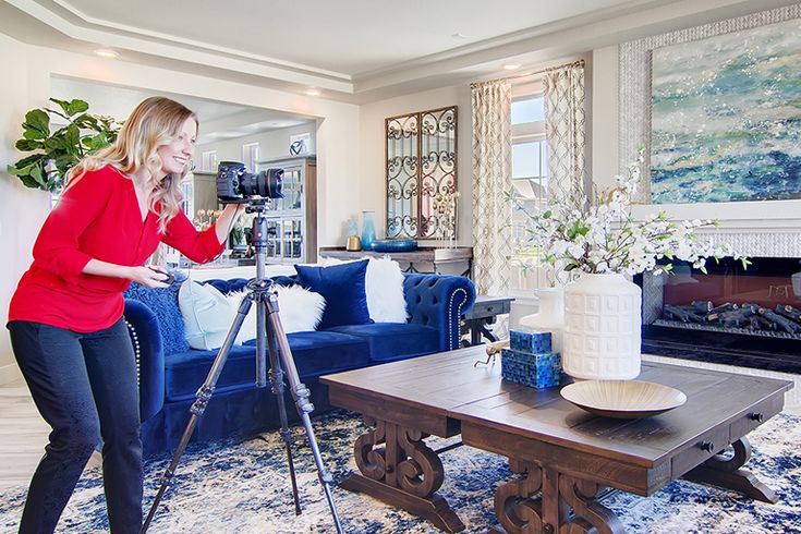 a woman standing in front of a blue couch holding a camera next to a coffee table