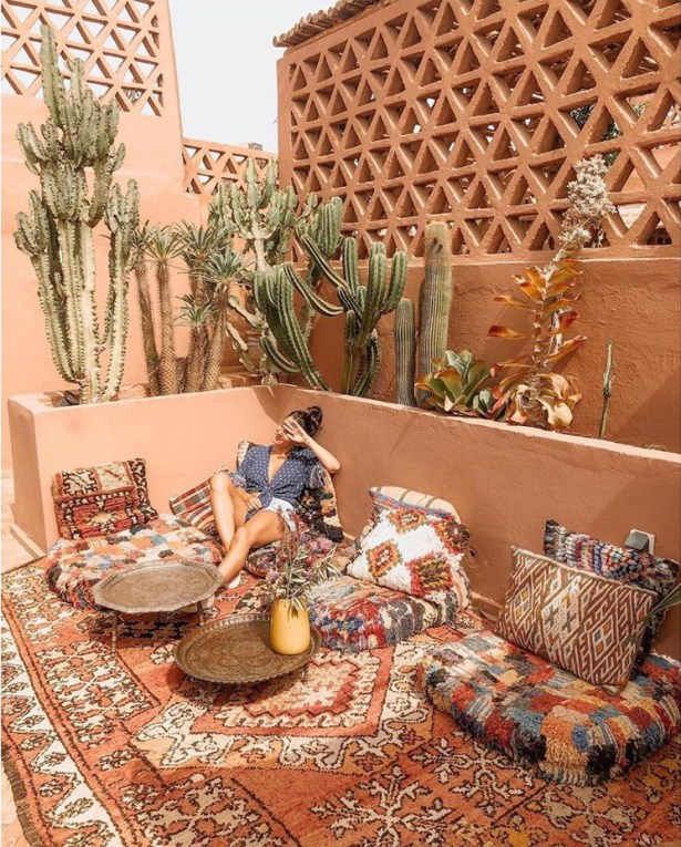 a woman sitting on a couch in front of some cactuses and potted plants