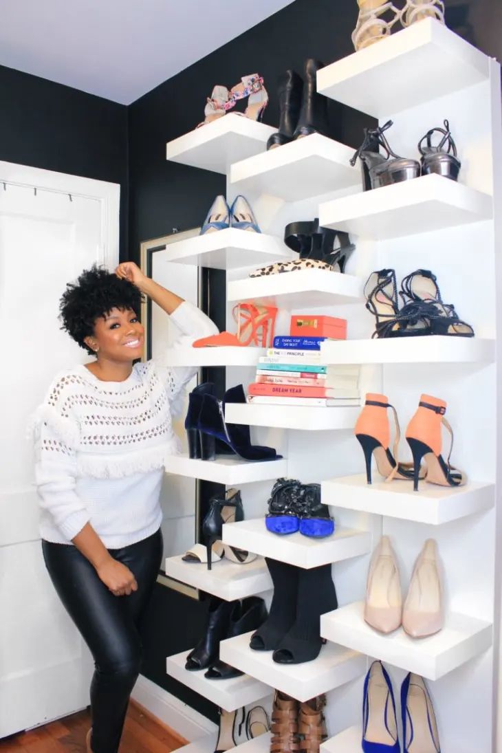 a woman standing next to a white shelf filled with shoes