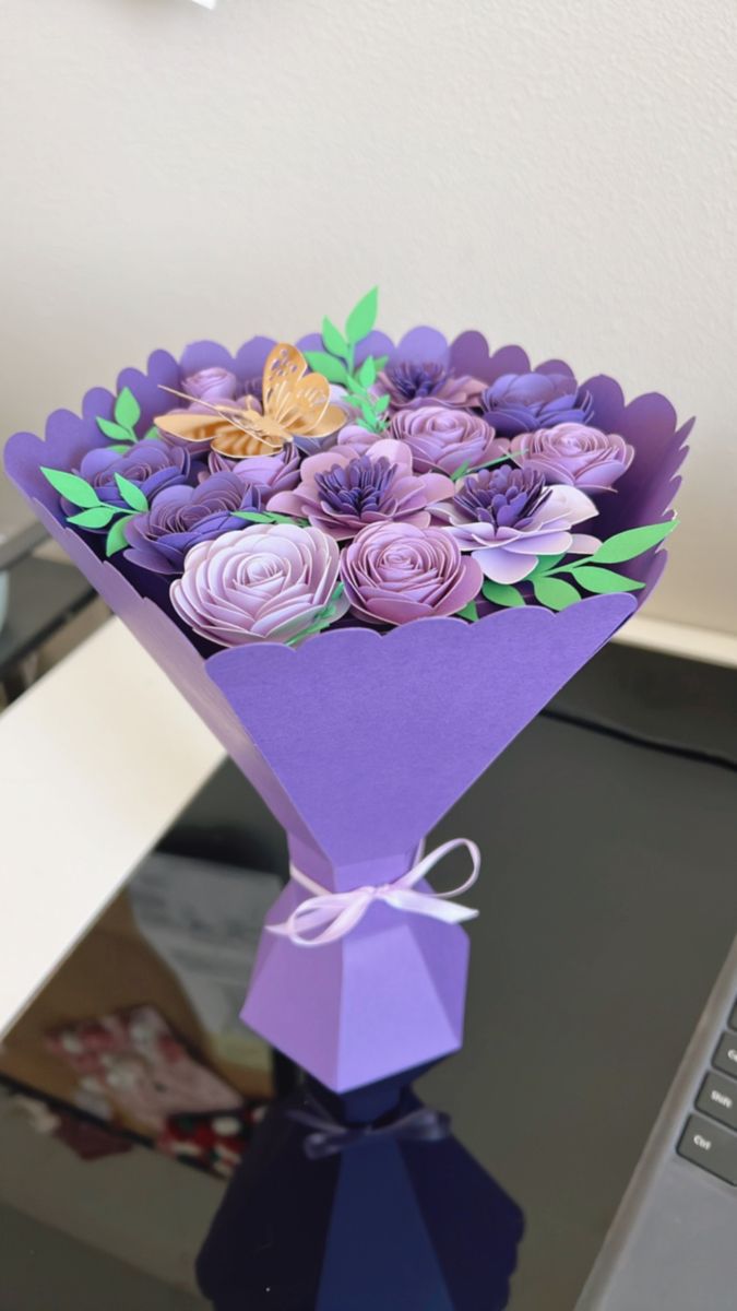 a bouquet of paper flowers sitting on top of a table next to a laptop computer