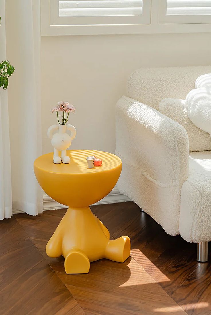 a yellow table sitting on top of a hard wood floor next to a white couch