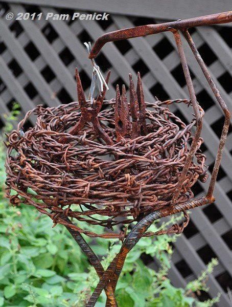 a bird's nest made out of branches in the middle of a garden area