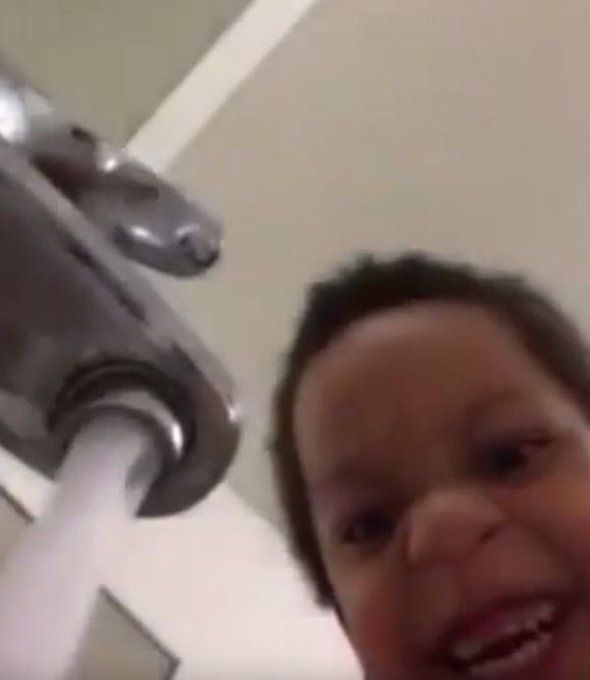 a young child is smiling in front of a faucet
