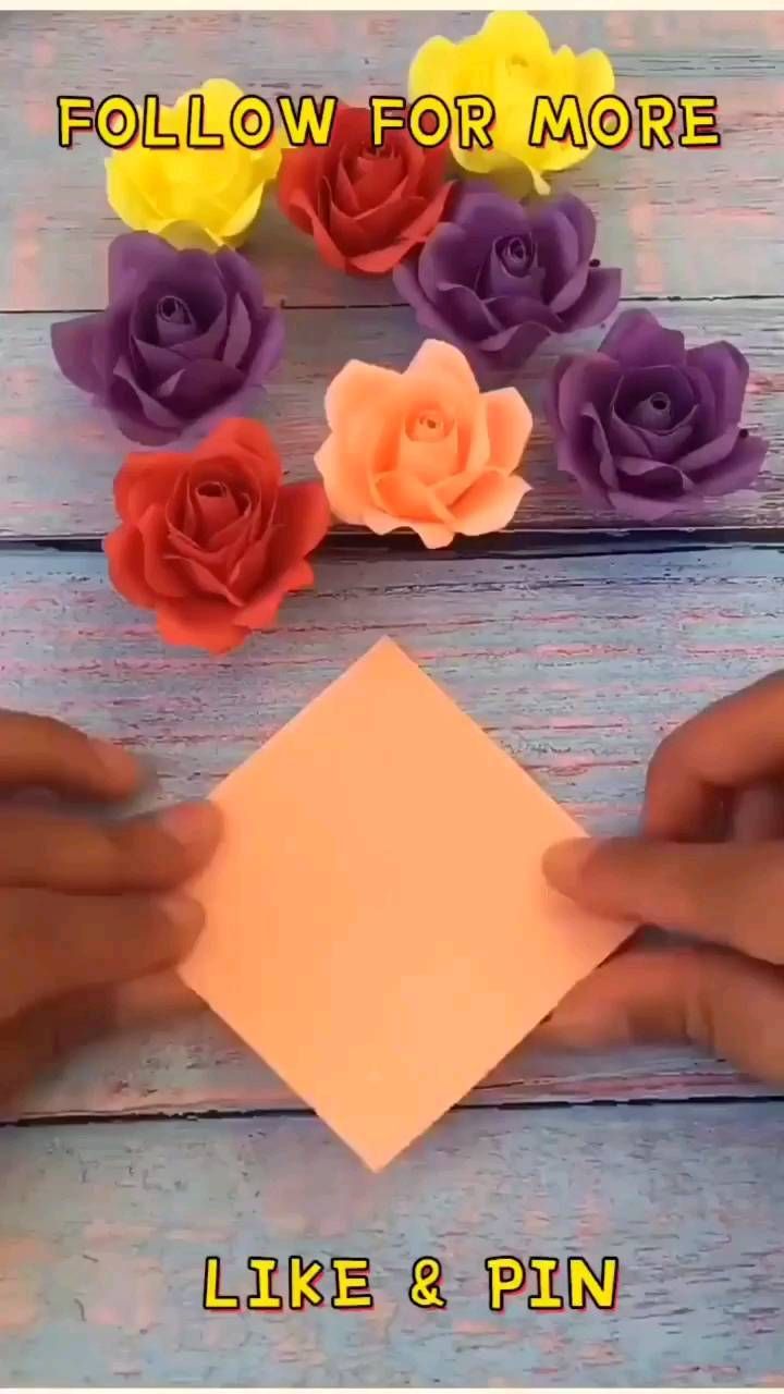 someone is making paper flowers out of colored paper on a wooden table with scissors and glue