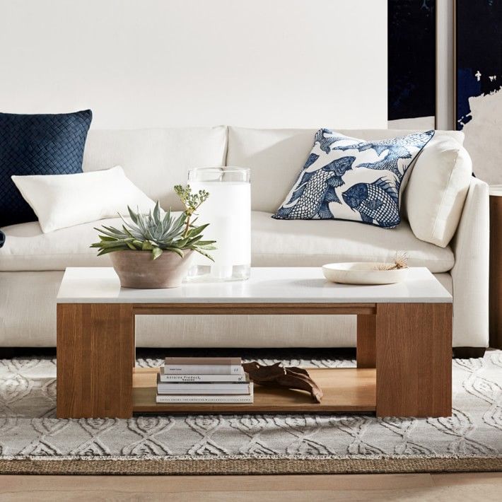 a living room with white couches and blue pillows on the floor, along with a coffee table