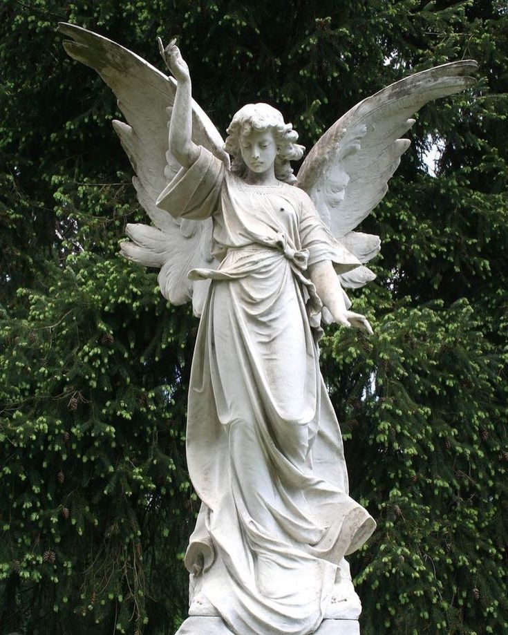 an angel statue in front of some trees