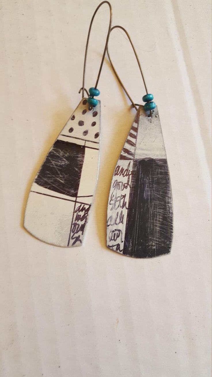 two wooden earrings with black, white and blue designs on the front one is hanging from a hook