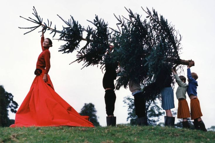four people in long dresses are picking up trees