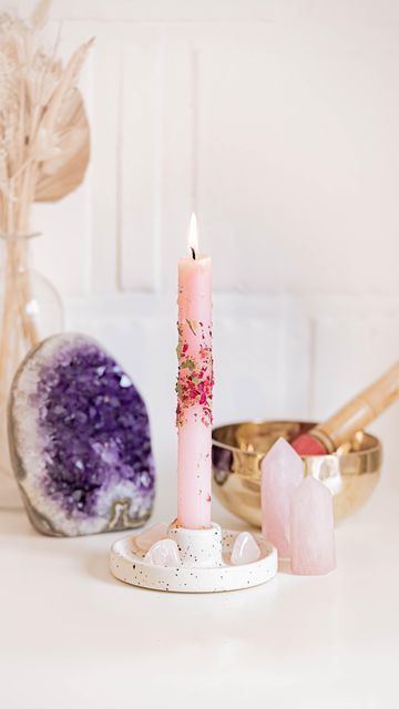 a pink candle sitting on top of a white table next to other items and decor