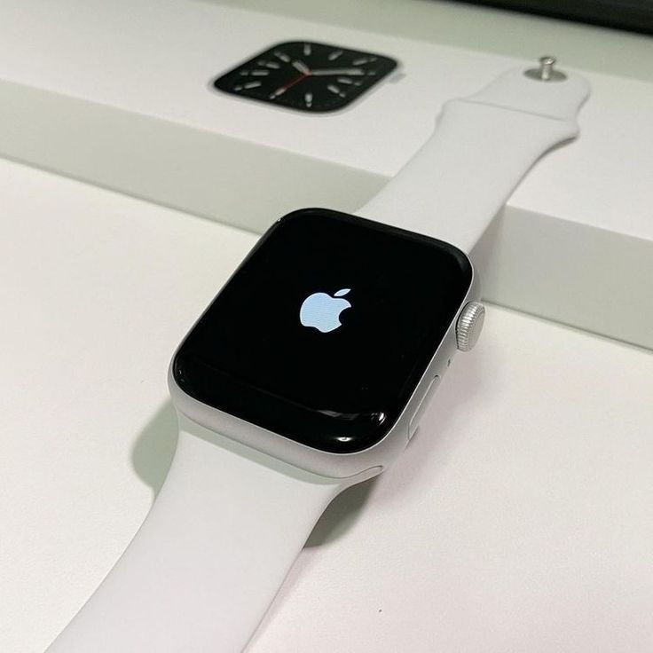 an apple watch sitting on top of a white table next to a black and white clock