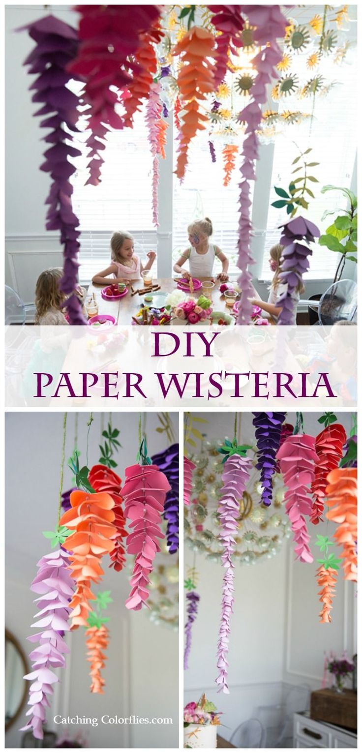 some paper flowers hanging from the ceiling and in front of a window with text overlay that reads diy paper wisteria