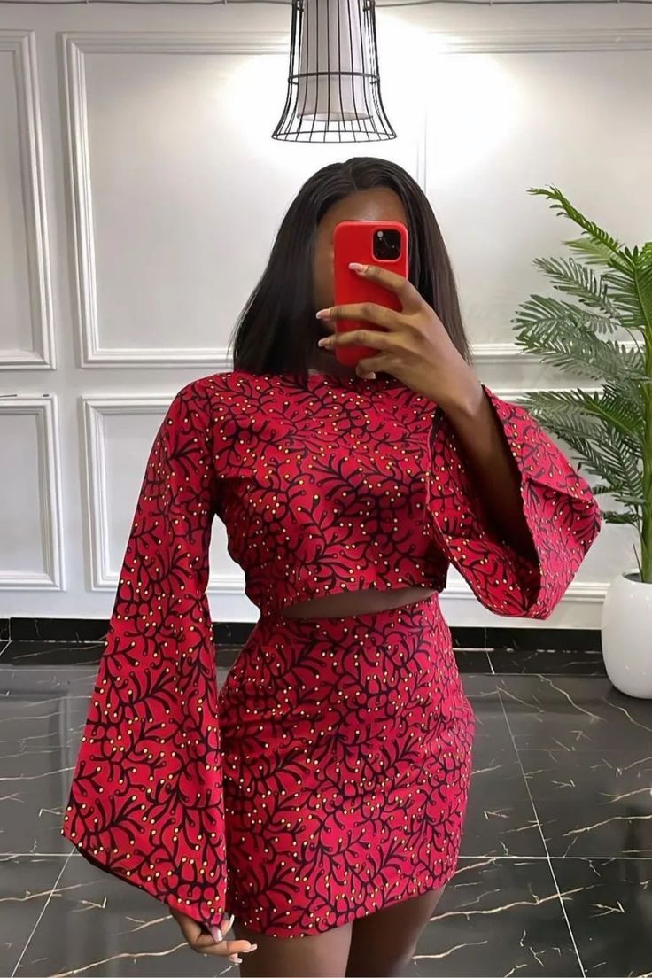 a woman taking a selfie wearing a red floral print dress with bell sleeves and cutouts
