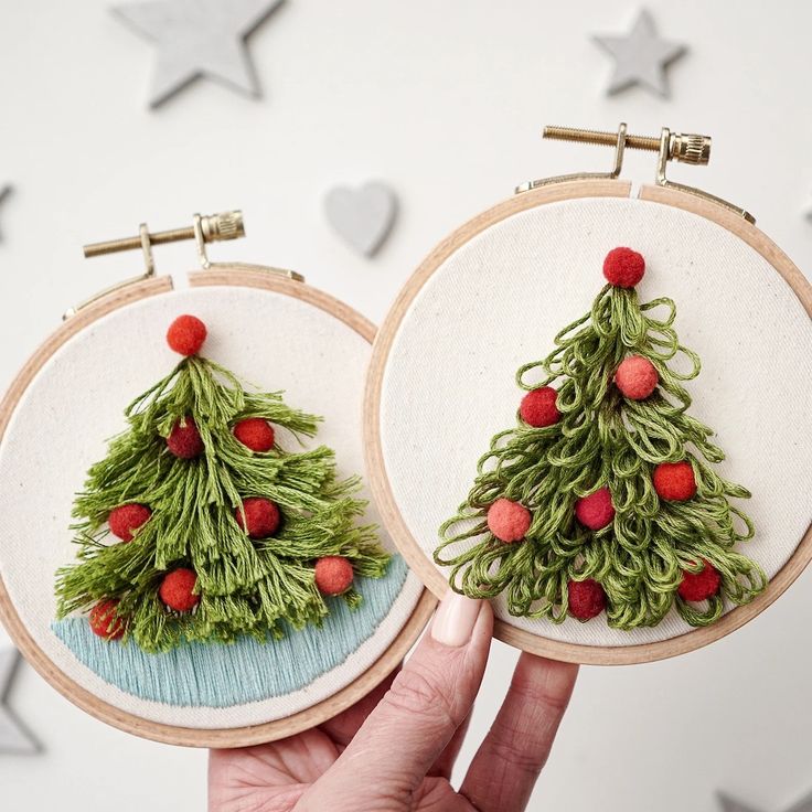 two hand embroidered christmas trees on hoop frames with red berries and green grass in the center