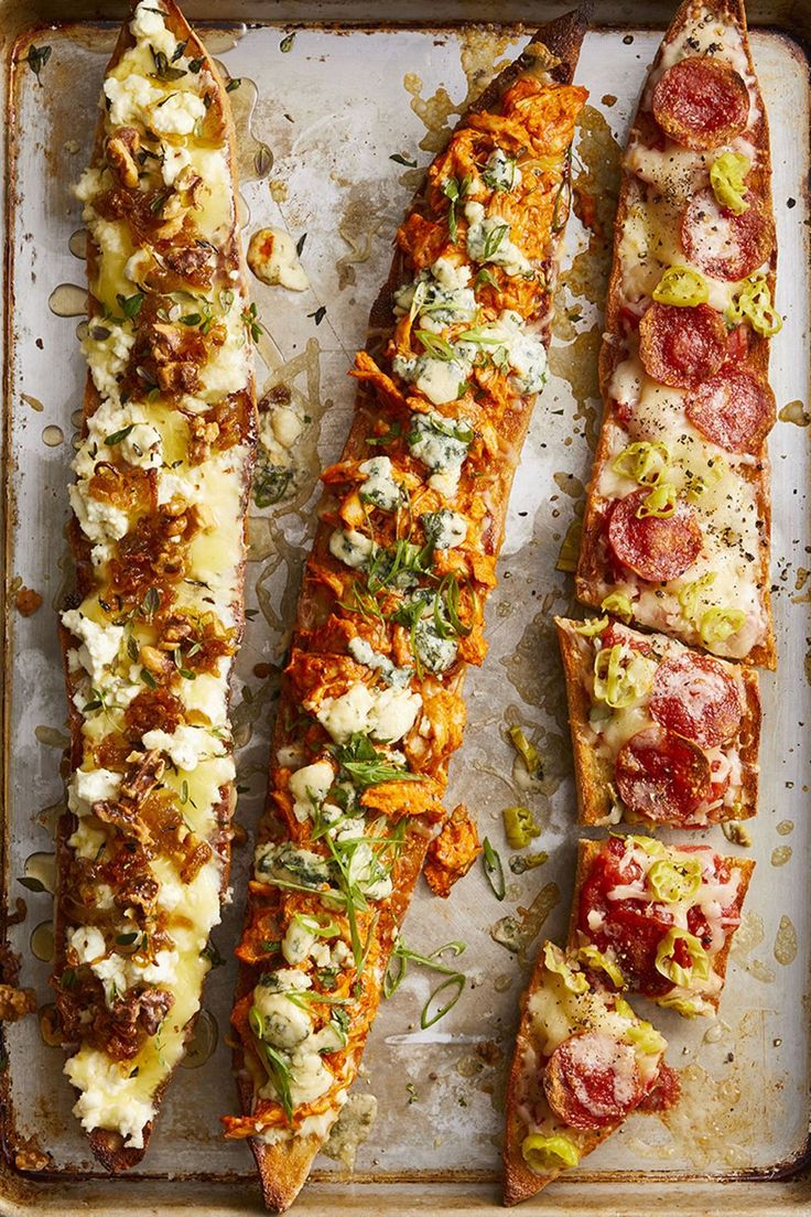 three long slices of pizza on a baking sheet with toppings and seasoning sprinkles
