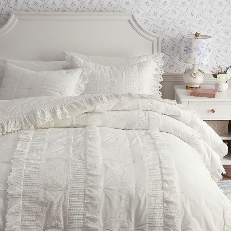 a white bed with ruffled sheets and pillows