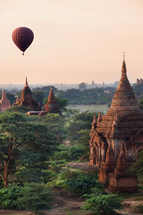 a hot air balloon flying over some temples